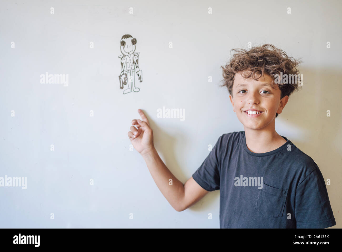 Portrait of smiling boy pointing to a drawing on a whiteboard Stock Photo