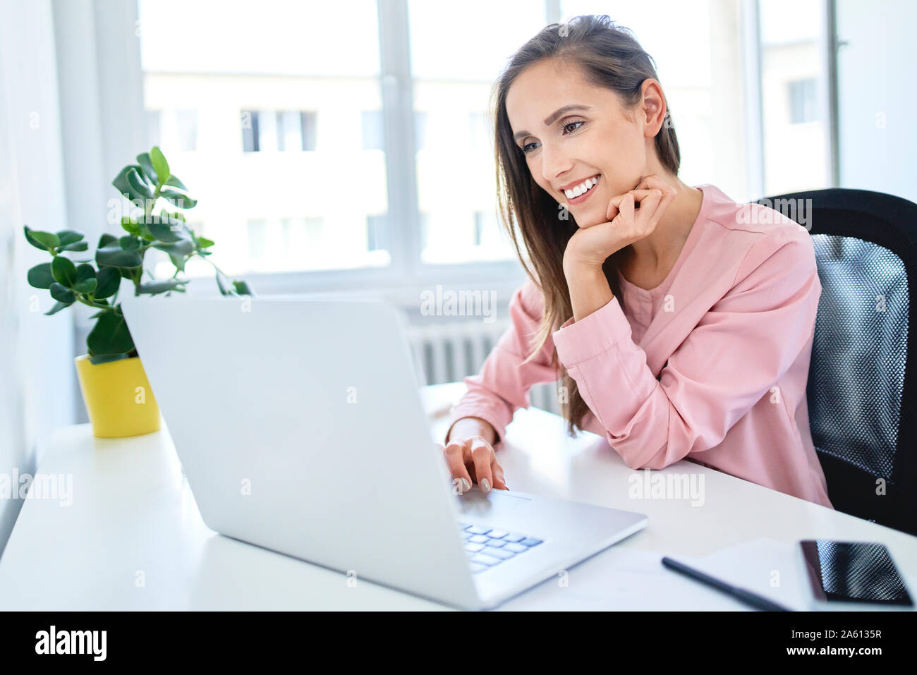 Happy young businesswoman working with laptop in office Stock Photo