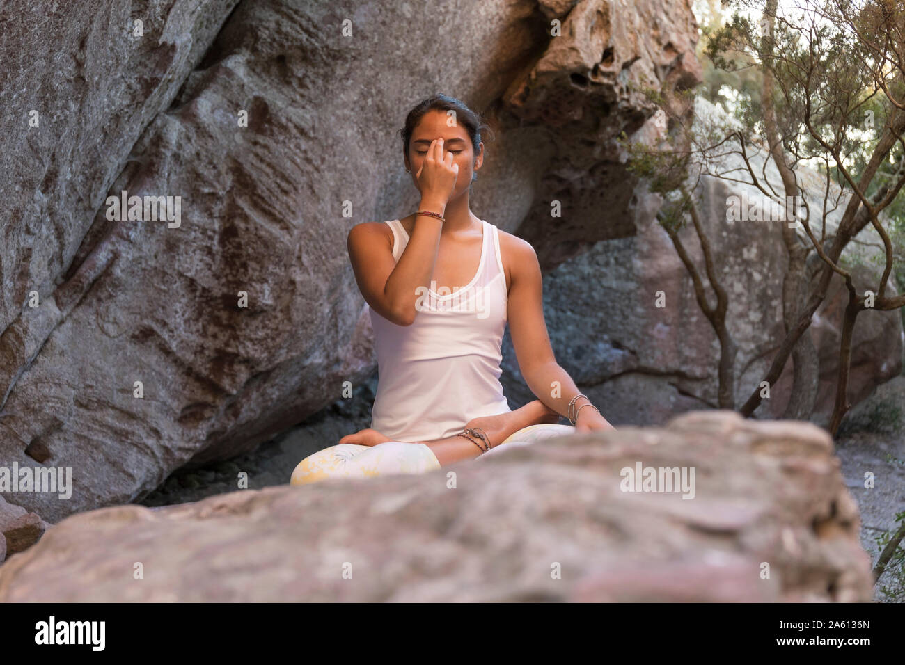 Young Asian woman practising yoga on a rock, breathing Stock Photo