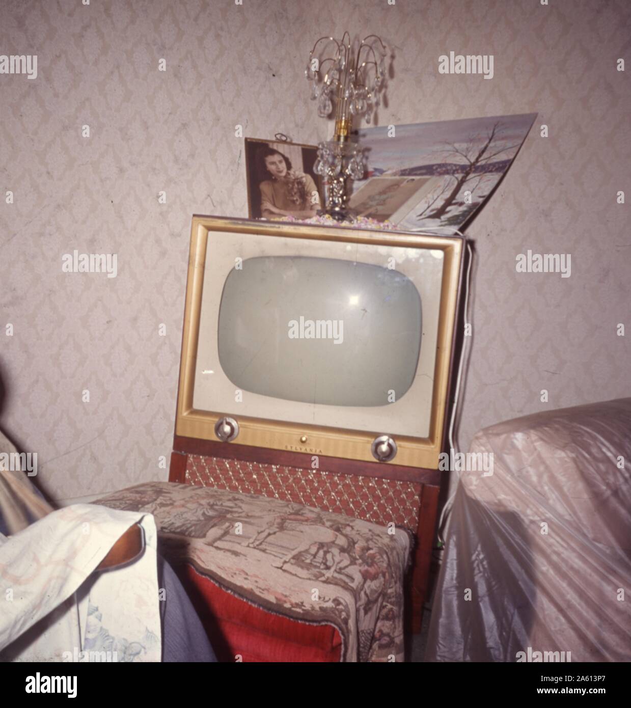 Television with two knobs and small screen in a domestic living room, covered with photographs and family heirlooms, 1965. () Stock Photo