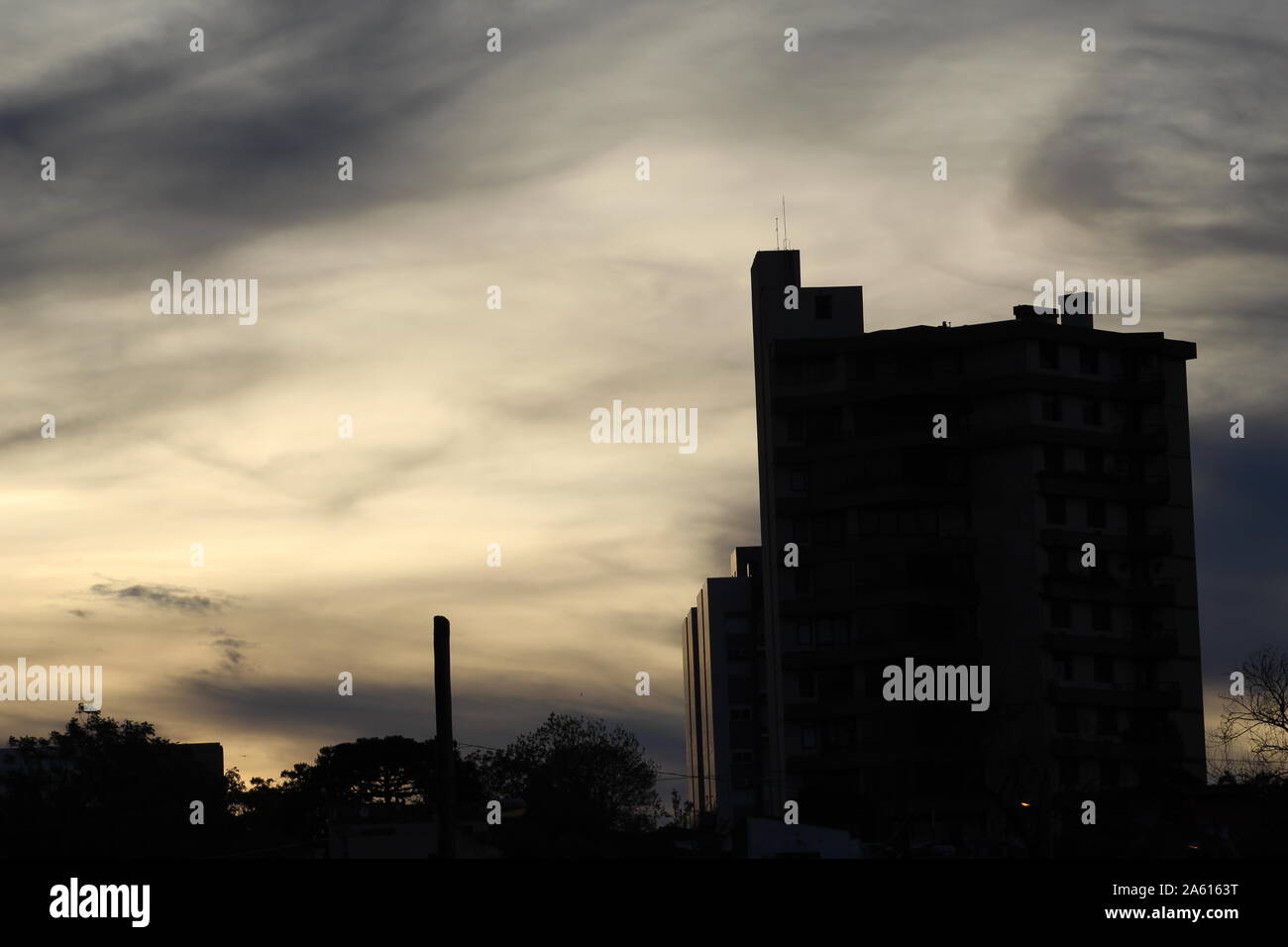 City dusk with a darkened building, sunlight refleting from behind illustrating altostratus cloud skies and their beautifully colored luminosity Stock Photo