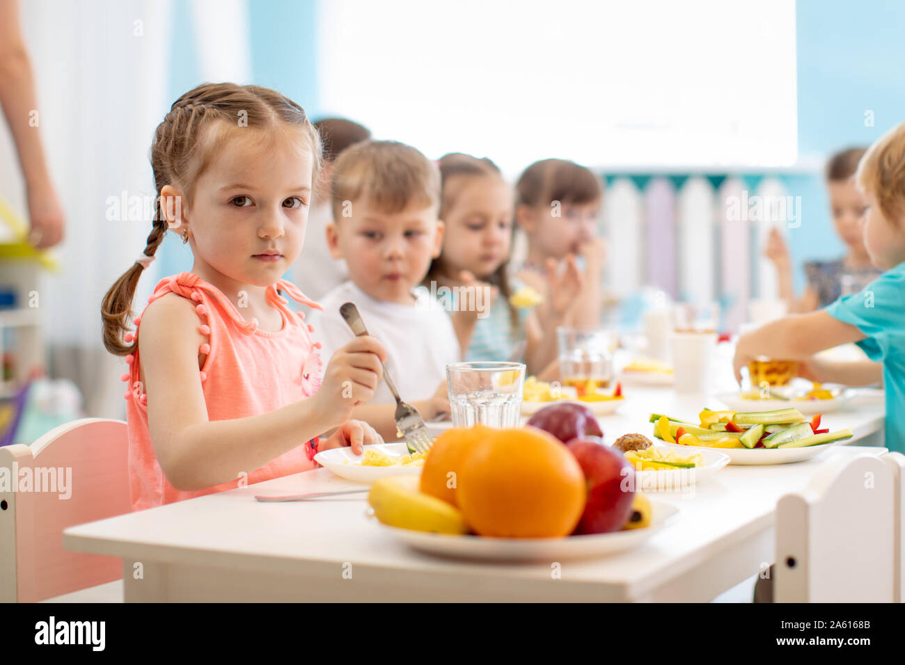 Group of kids have lunch in daycare. Children eat healthy food in