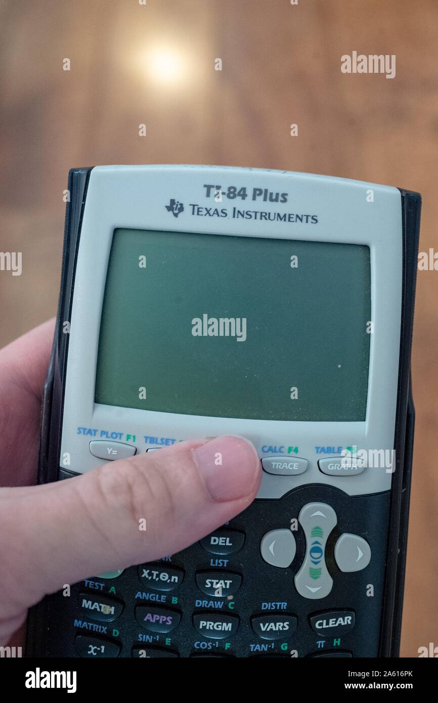 Close-up of hand of a man holding TI84+ graphing calculator from Texas Instruments, ca 2010, a standard calculator frequently used in schools and on standardized tests including the SAT, San Ramon, California, August 27, 2019. () Stock Photo