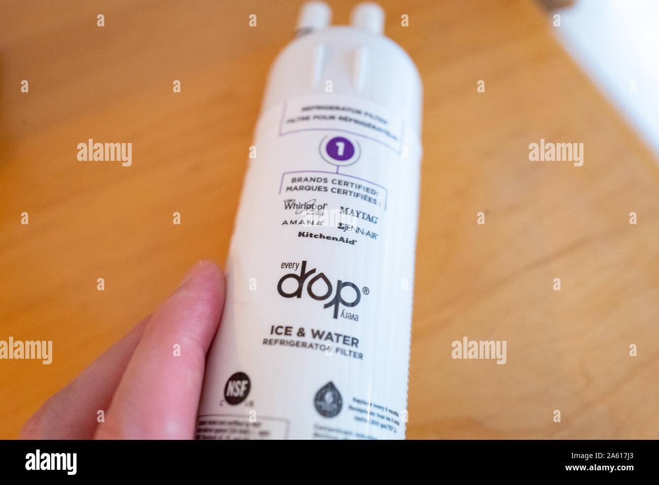 Close-up of hand of a man holding an Every Drop refrigerator filter with logos for brands including Whirlpool and Maytag, on light wooden surface, August 27, 2019. () Stock Photo