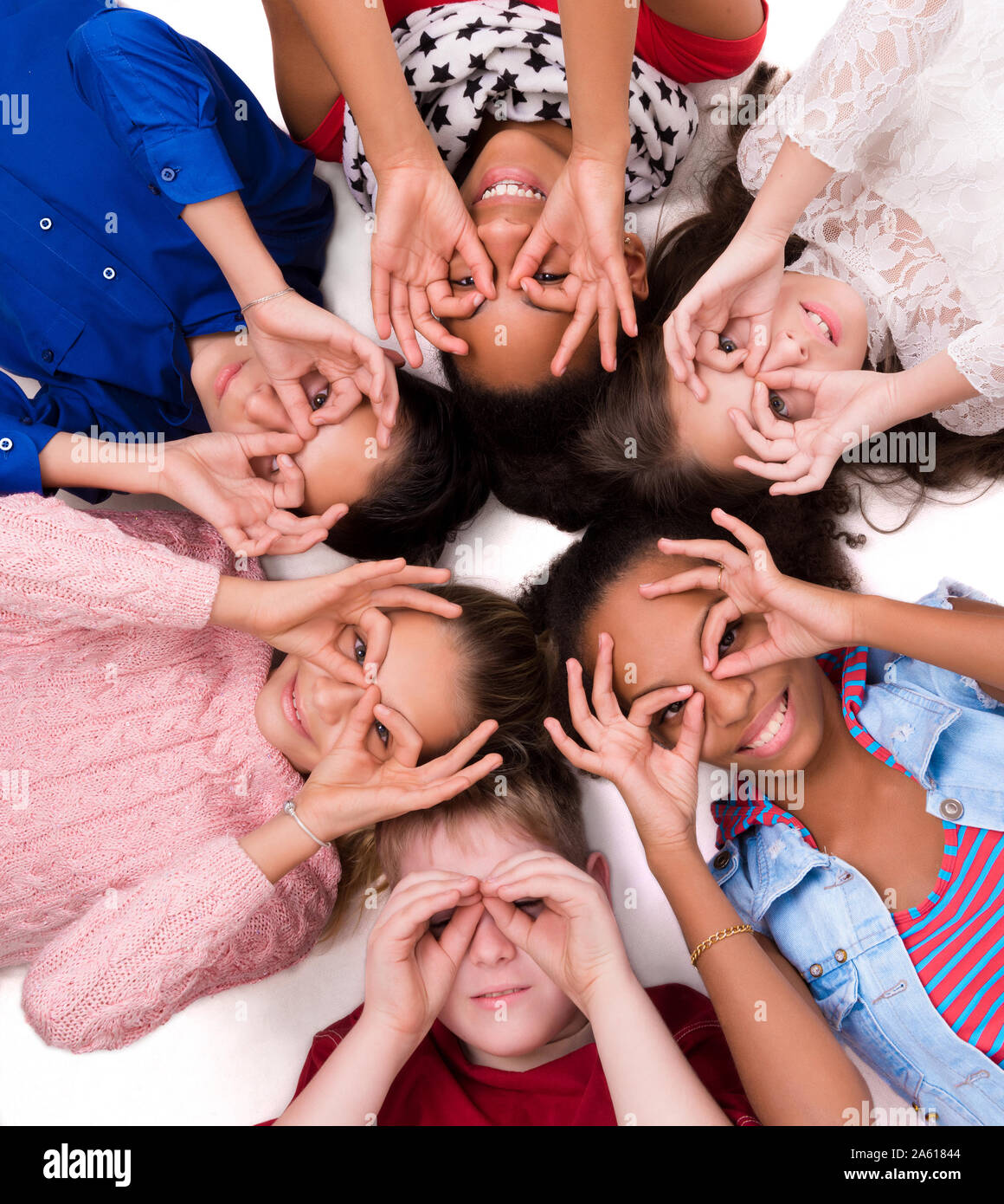 teenage children lying on the floor head to head with glasses out of fingers Stock Photo