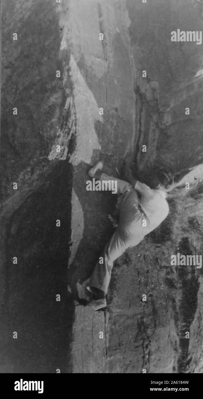 A man reaches his foot above his head on a rock face during a Northern Cavern and Fell Club rock climbing and spelunking event in Yorkshire, United Kingdom, 1934. () Stock Photo