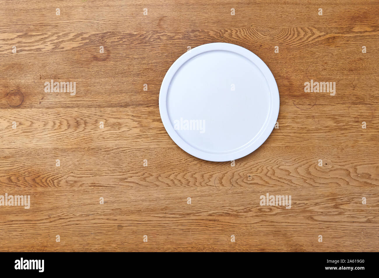 Empty white plate on textured wooden table Stock Photo