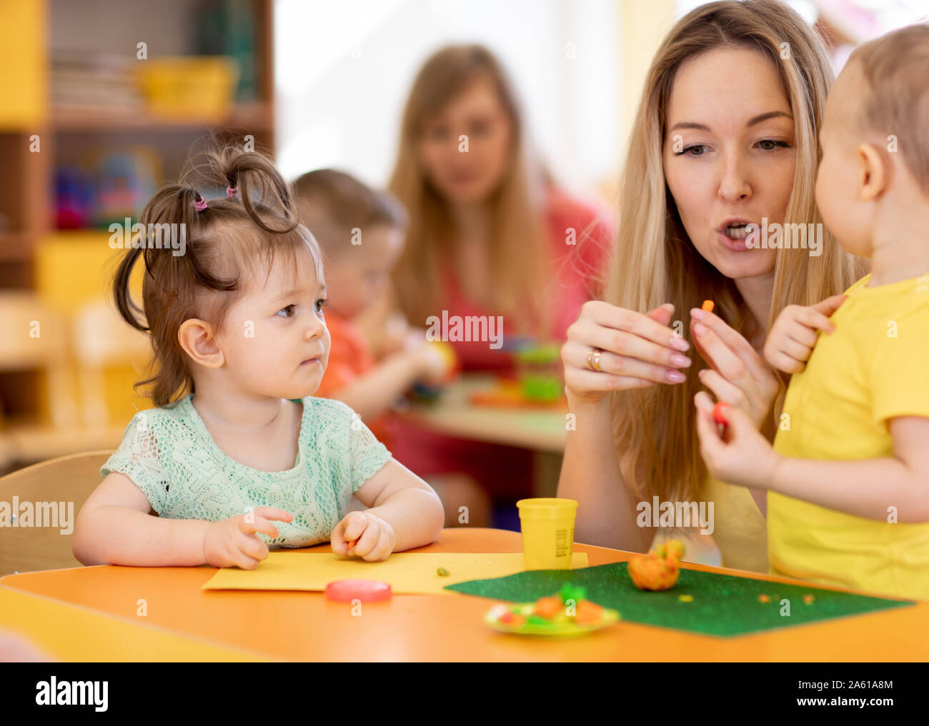 Kids with teacher playing with play clay in kindergarten or playschool ...