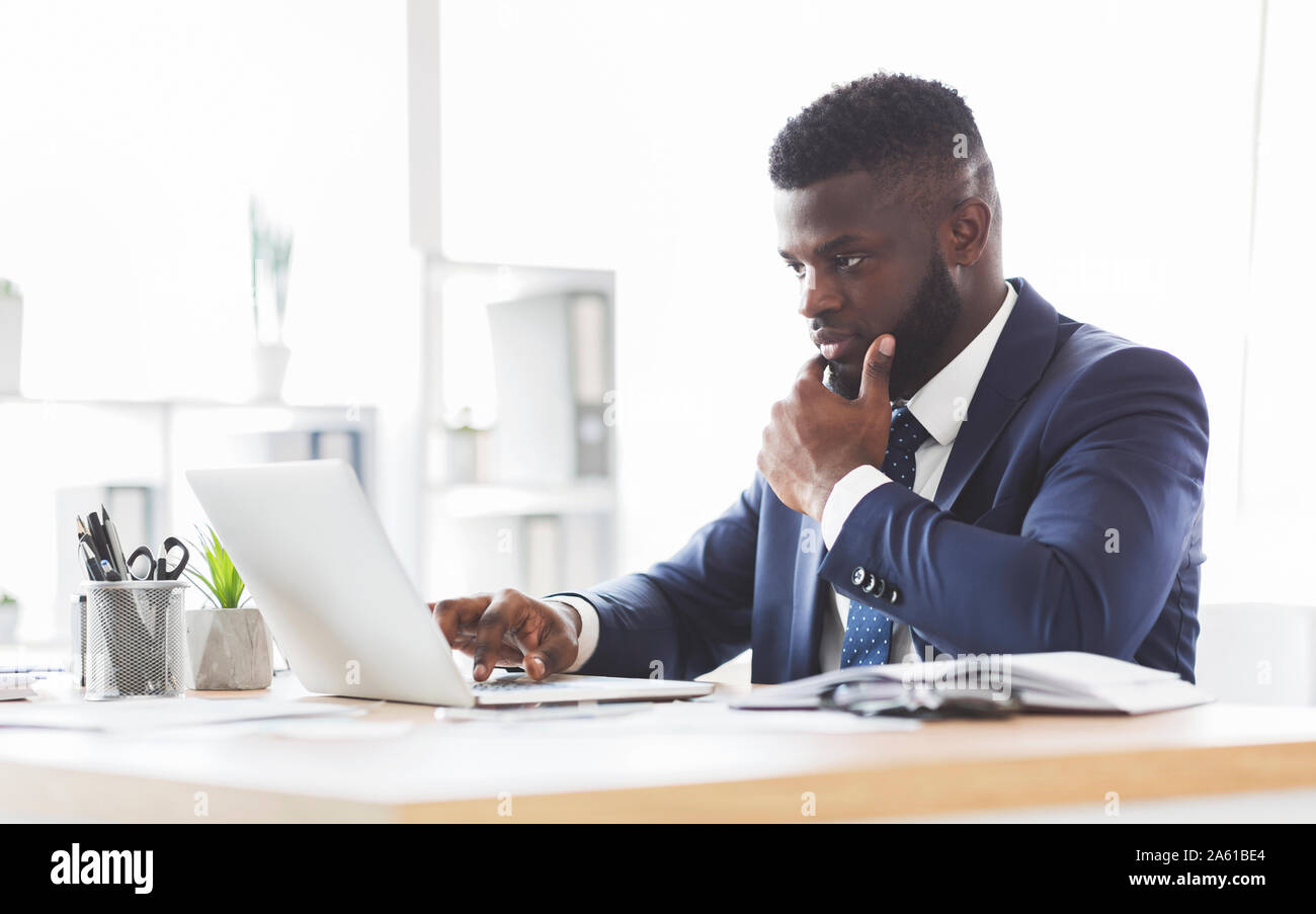 Thoughtful young manager making research online, using laptop Stock Photo