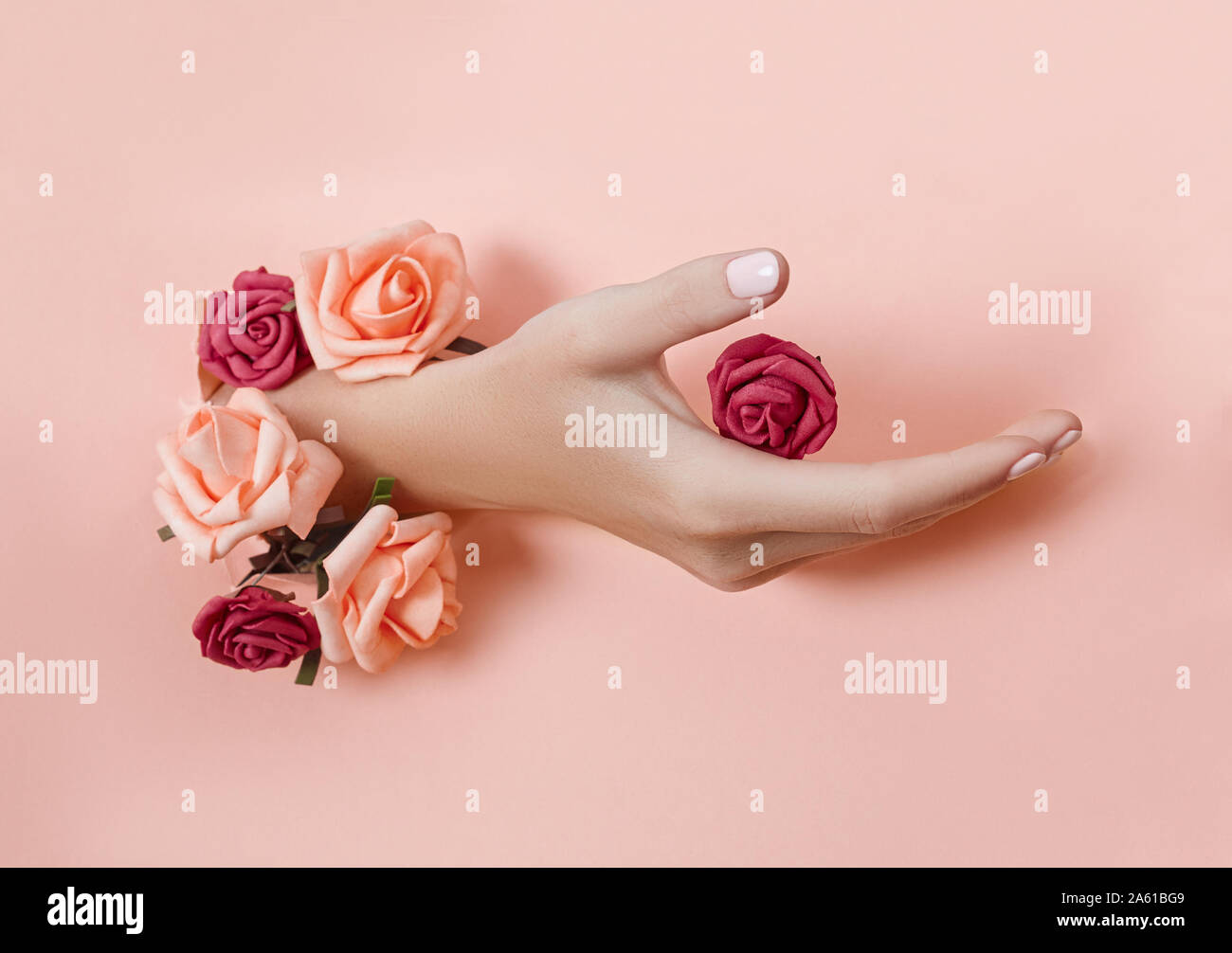 Hand with paper flowers and painted nails is thrust through a hole in