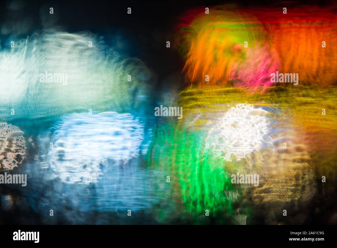 abstract out of focus bold coloured lights shot on the street rain on a car window, high quality good for backgrounds and eye catching advertising. Stock Photo