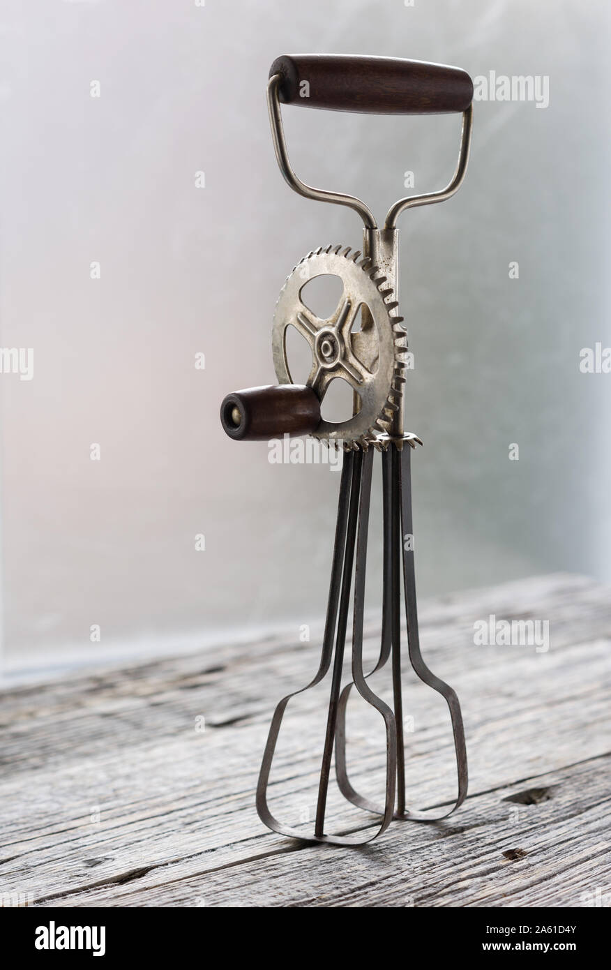 https://c8.alamy.com/comp/2A61D4Y/vintage-manual-whisk-eggs-beater-stand-on-the-the-rustic-wooden-table-vertical-with-copy-space-2A61D4Y.jpg
