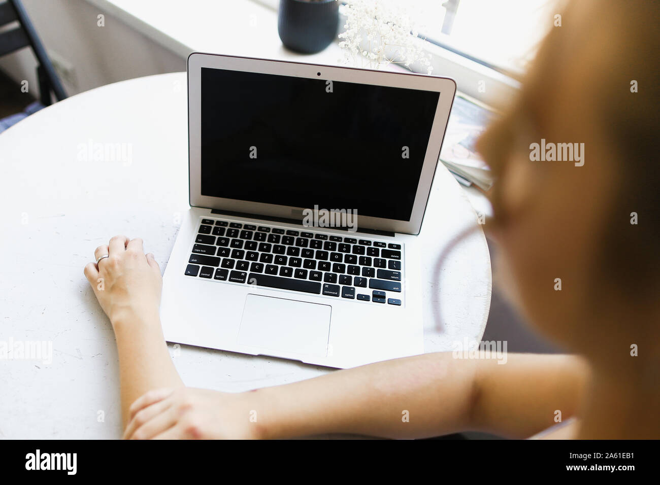 Blurried woman working with laptop, focus on computer. Stock Photo