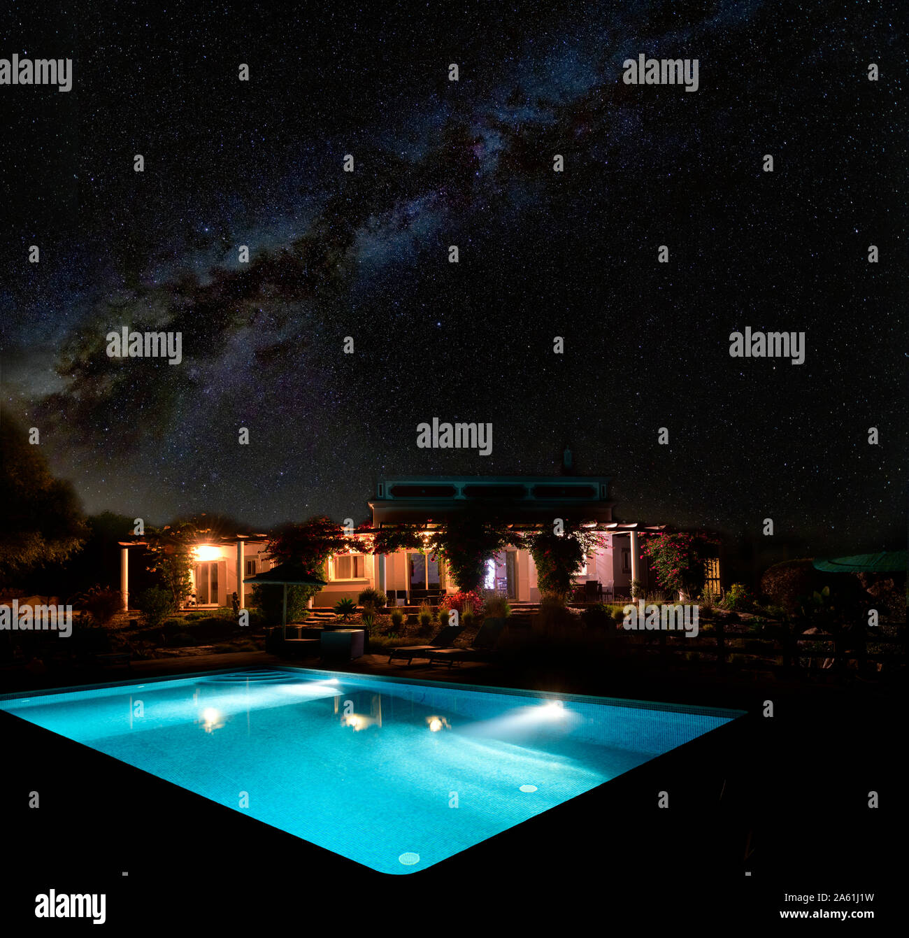 The milky way and night sky above an illuminated house villa and swimming pool. Algarve Portugal Stock Photo