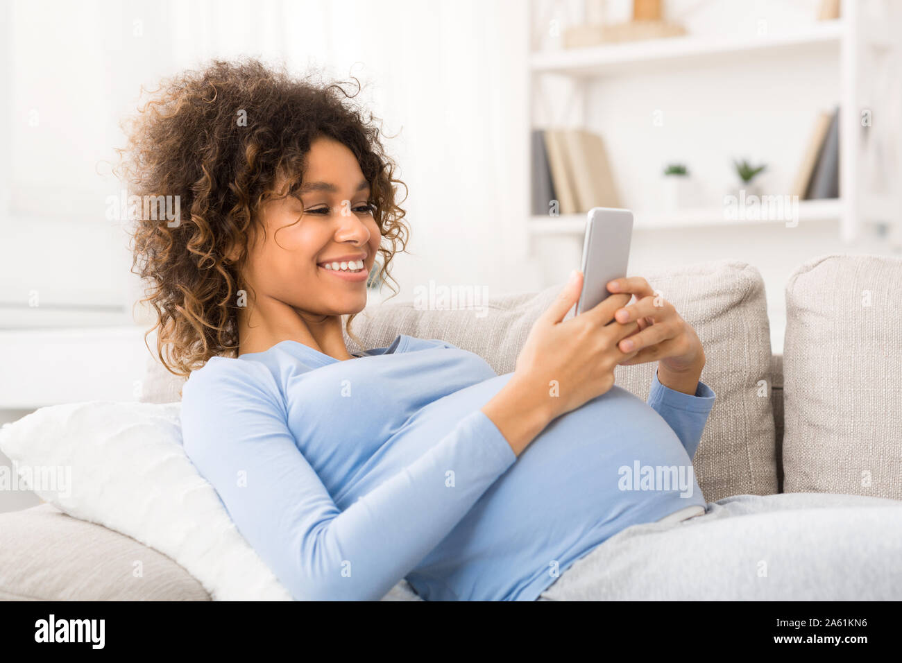 Happy pregnant woman surfing the net on smartphone Stock Photo