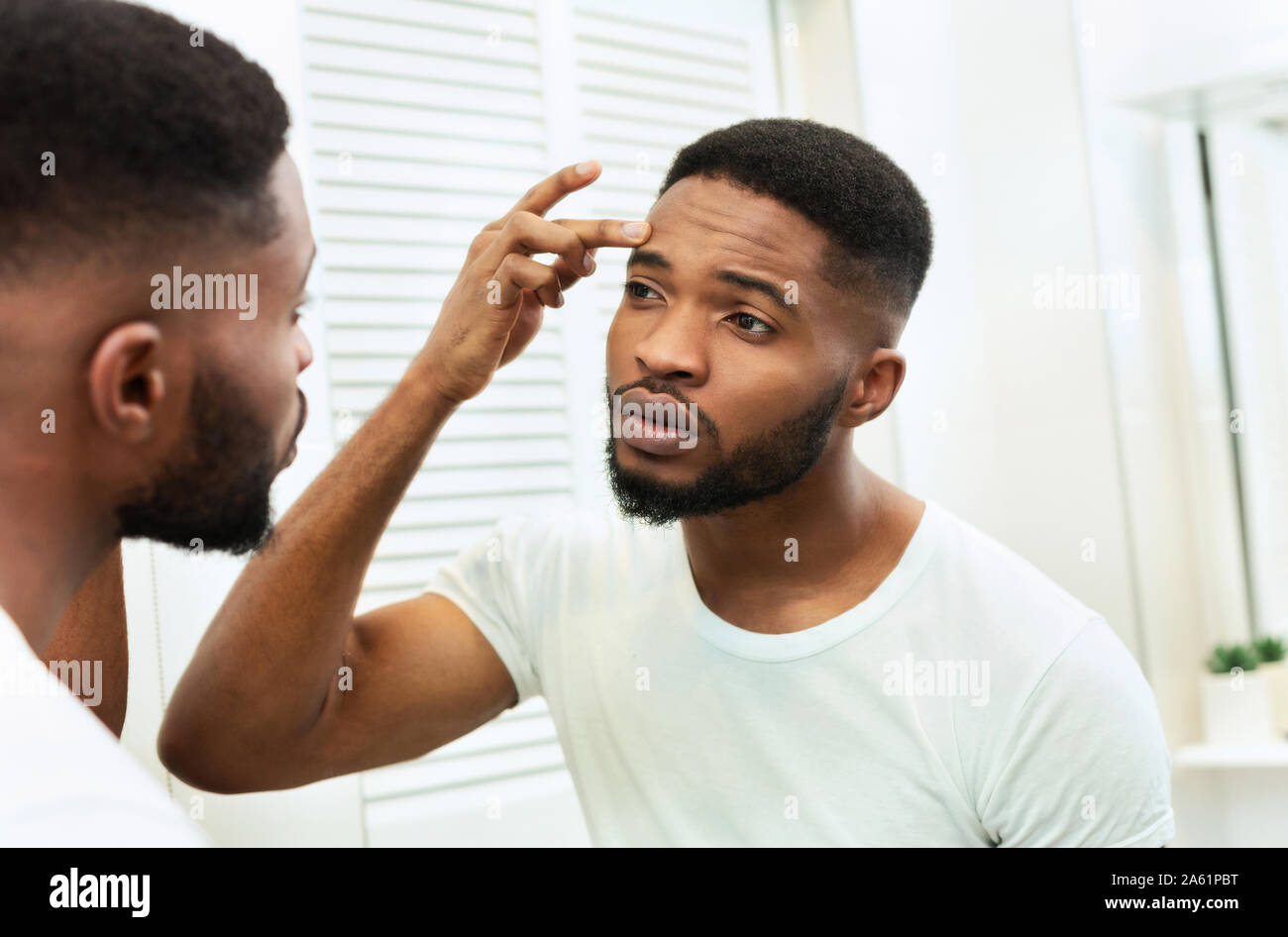 Young worried african man checking his wrinkles Stock Photo