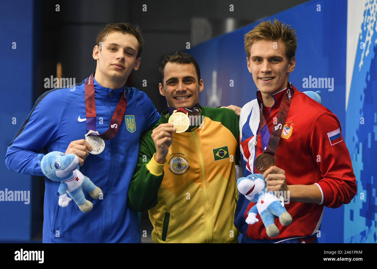 Wuhan, China's Hubei Province. 23rd Oct, 2019. Gold medalist Leonardo De Deus (C) of Brazil, silver medalist Denys Kesil (L) of Ukraine and bronze medalist Daniil Pakhomov of Russia attend the awarding ceremony of men's 200m butterfly final of swimming at the 7th CISM Military World Games in Wuhan, capital of central China's Hubei Province, Oct. 23, 2019. Credit: Cheng Min/Xinhua/Alamy Live News Stock Photo
