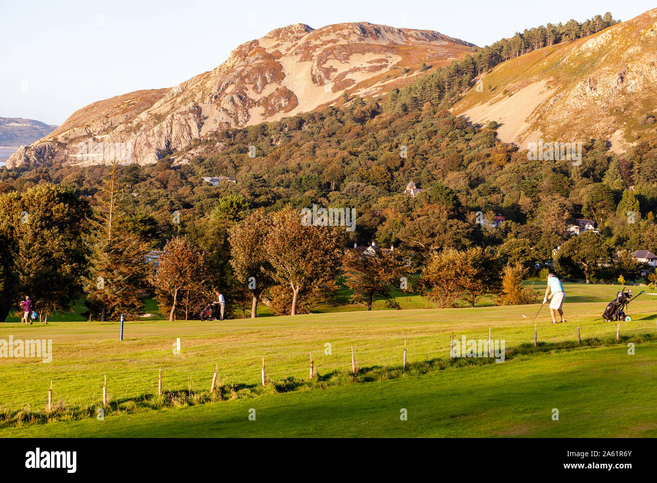Penmaenmawr, North Wales, UK- September, 13 2019 Men playing golf in evening sunlight at Penmaenmawr Golf course Stock Photo