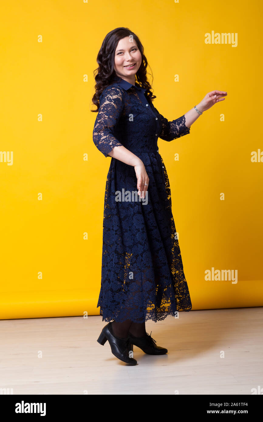 portrait of a beautiful Asian woman in a blue dress against a yellow ...