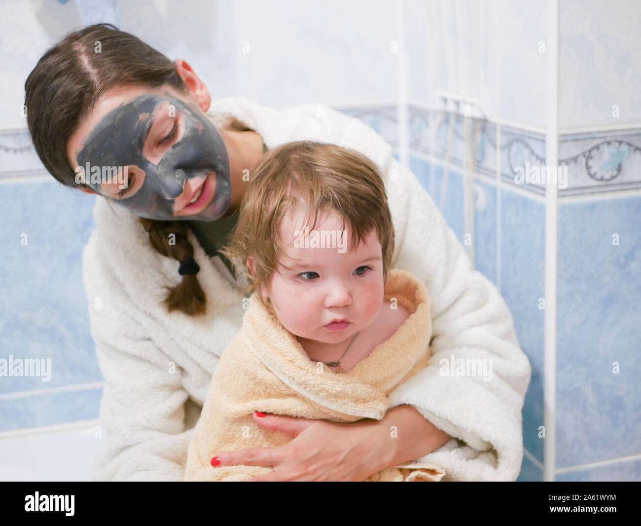 baby with mother in the bathroom. Mother holding her baby in a towel in