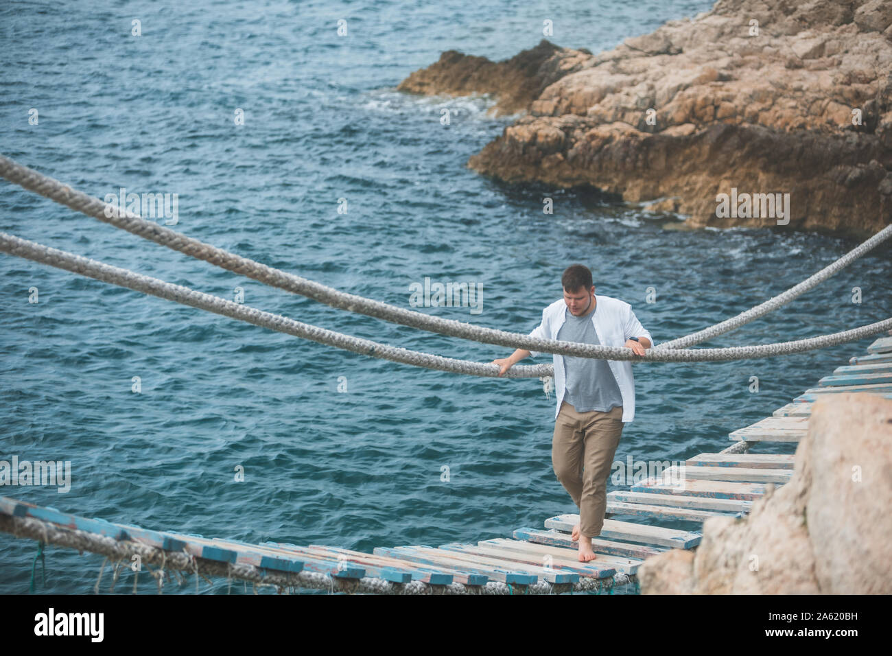 man walking by suspension bridge cross sea bay Stock Photo - Alamy
