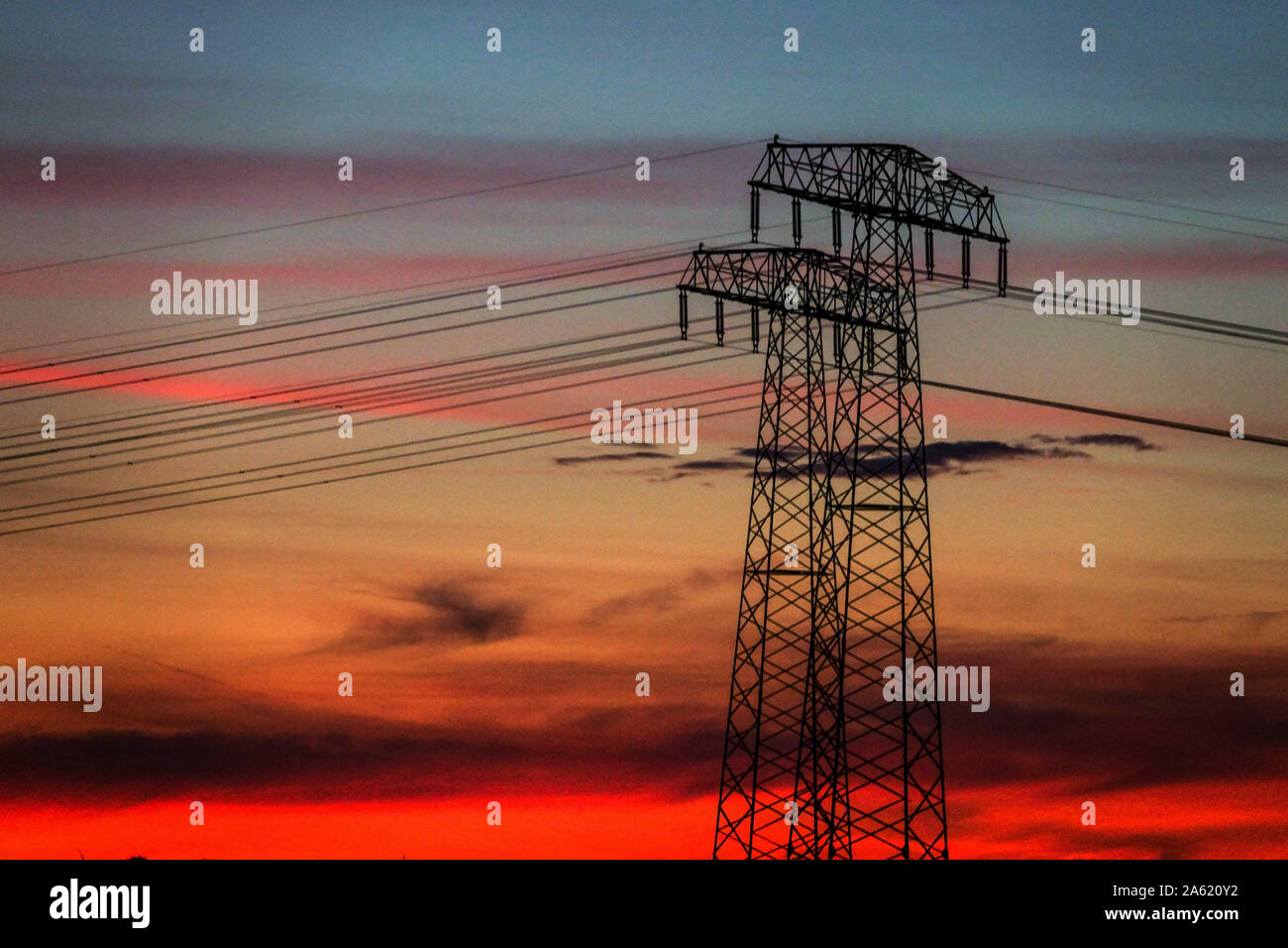 Power lines pylons in a sunset, red sky Germany Transmission lines Energy Stock Photo