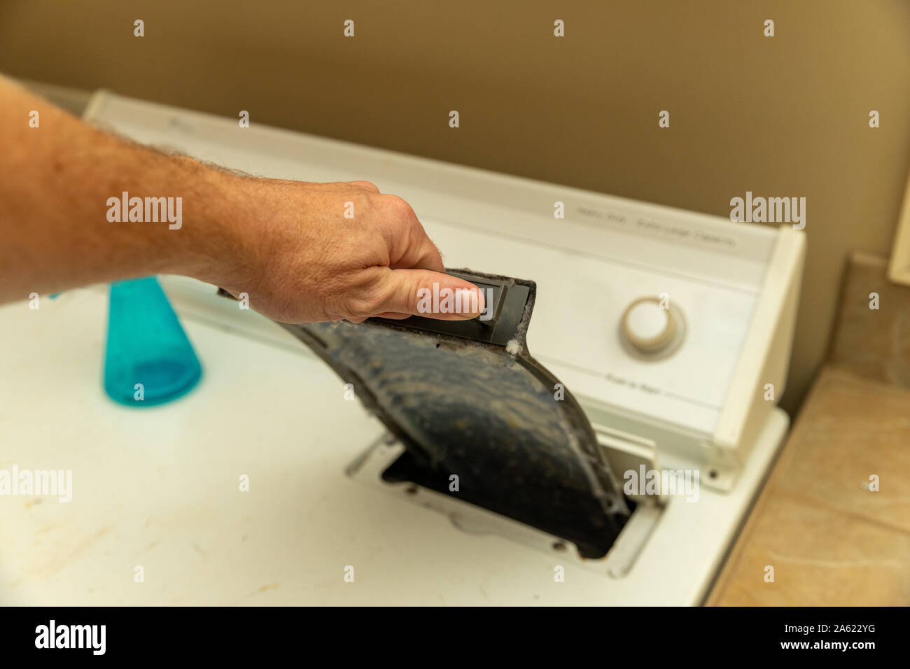 hand removing dirty lint screen of dryer while doing laundry Stock Photo