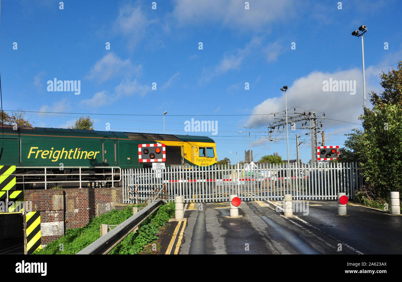 Freightliner class 66 hauls a freight by the now closed level crossing at Ely (cathedral west tower in distance), Cambridgeshire, England, UK Stock Photo