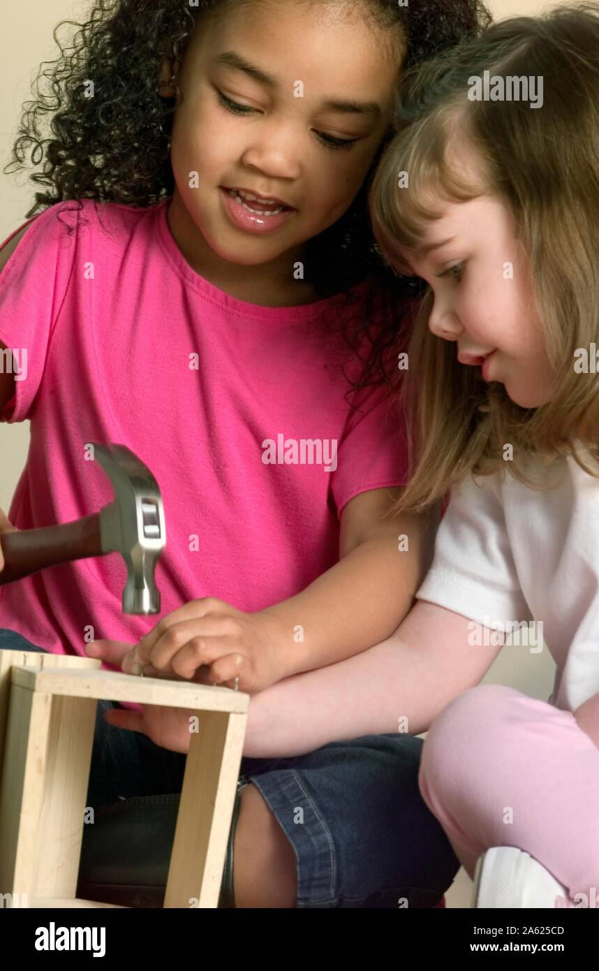 Multiethnic little girls using hammer and nails on a handy craft project Stock Photo Alamy