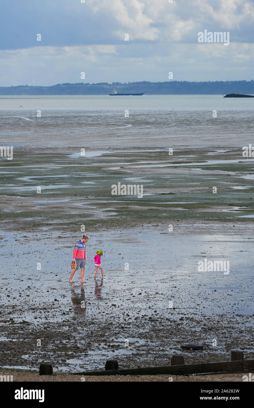 Father and daughter on the estuary mud flats while the river Thames tide is out at Thorpe Bay, Southend-on-sea, Essex, England. Stock Photo