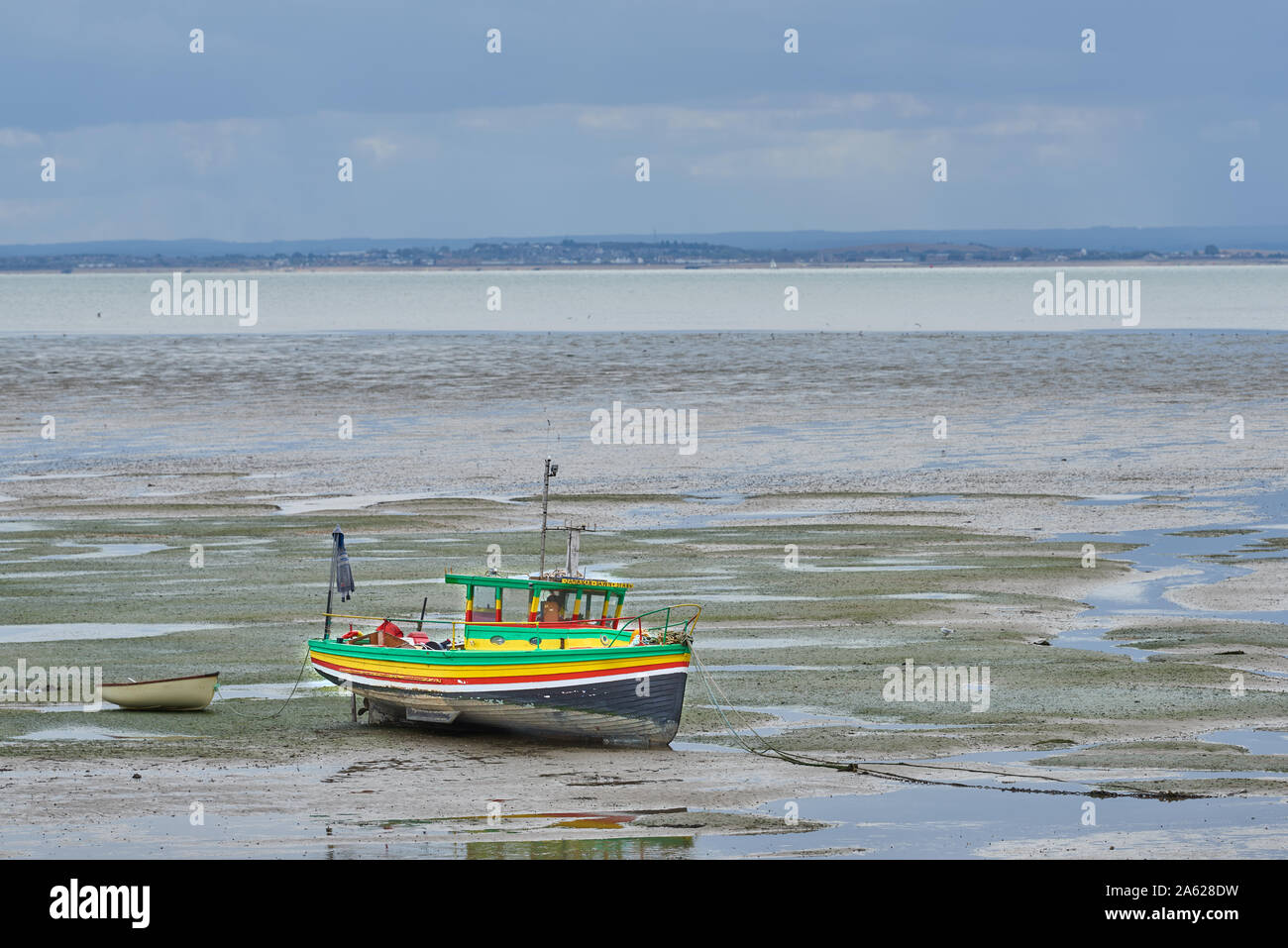 Colorful boat moored on the mud flats of the river Thames estuary at