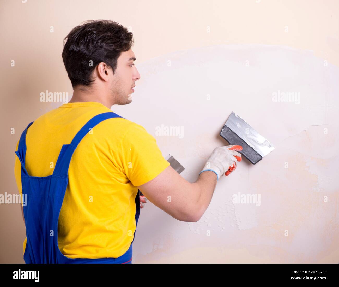 The young contractor employee applying plaster on wall Stock Photo