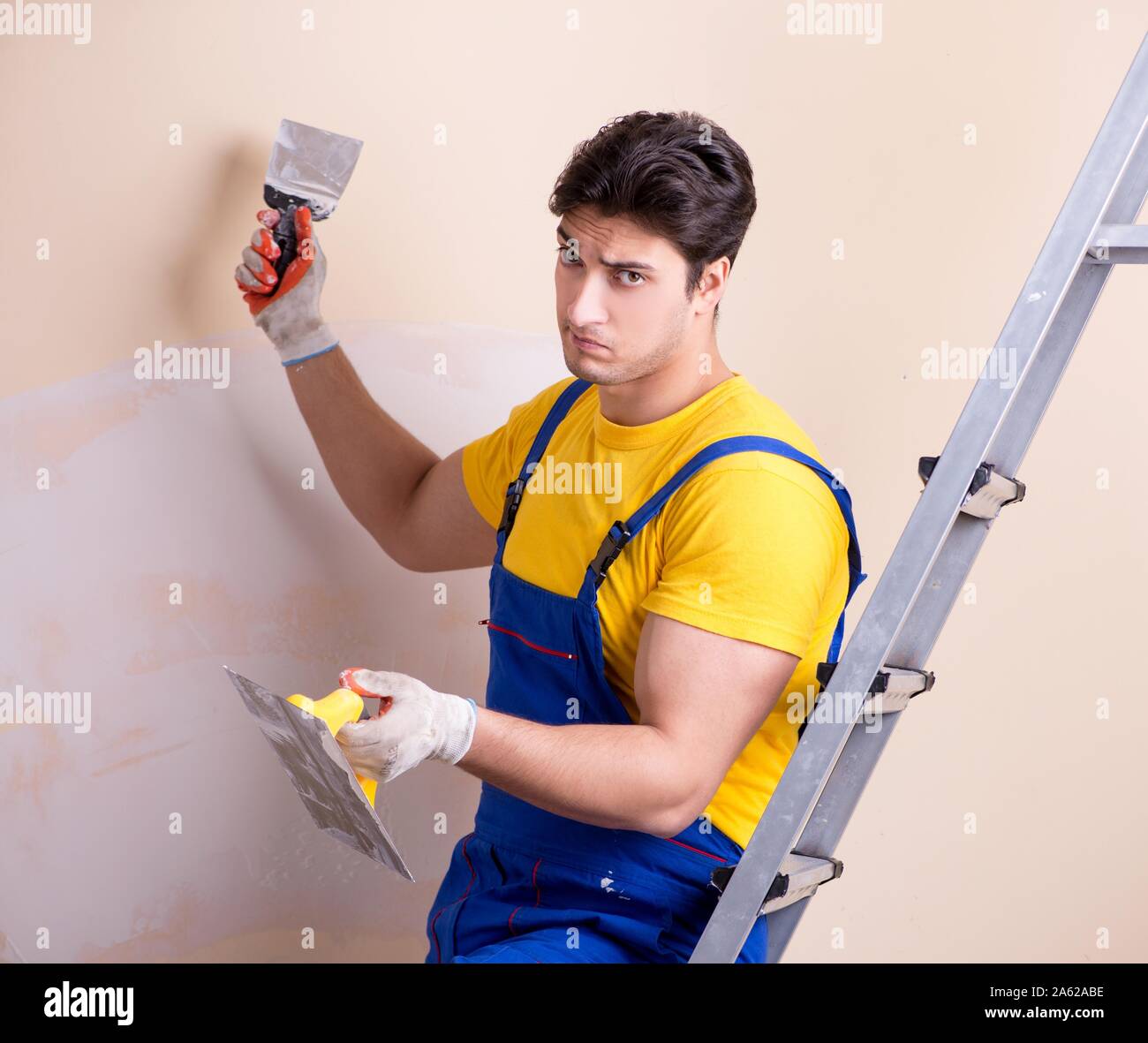The young contractor employee applying plaster on wall Stock Photo