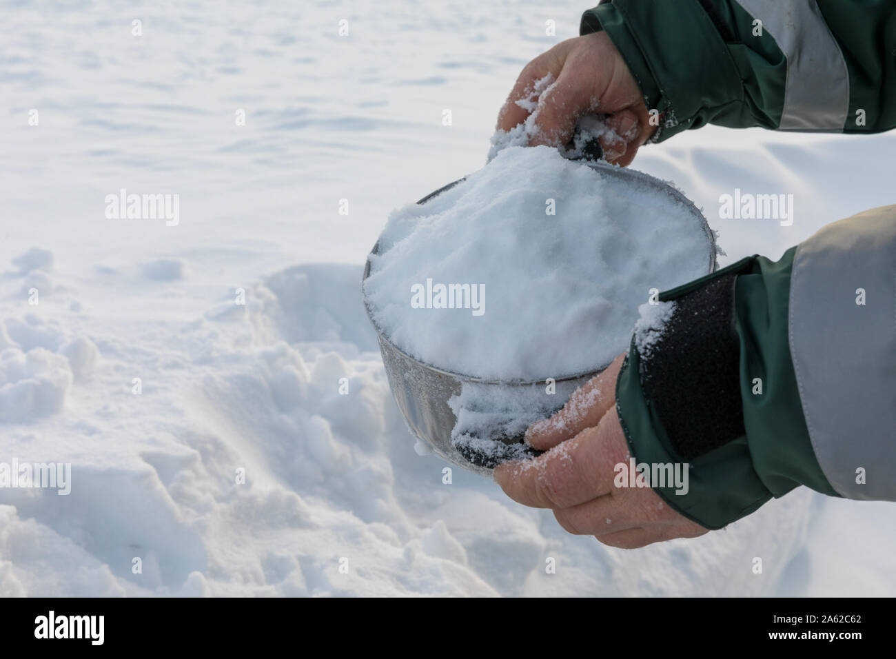 Man holding a pot full of snow, for melting into drinking water Stock
