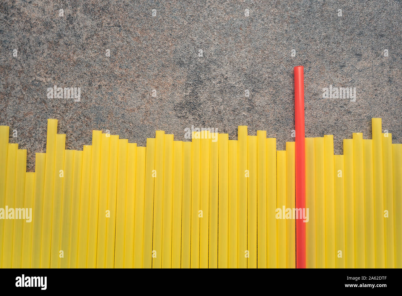 Arranging a situation where a leader is needed in a group of the same people without personality. Background with drinking straws. One red tube. Stock Photo