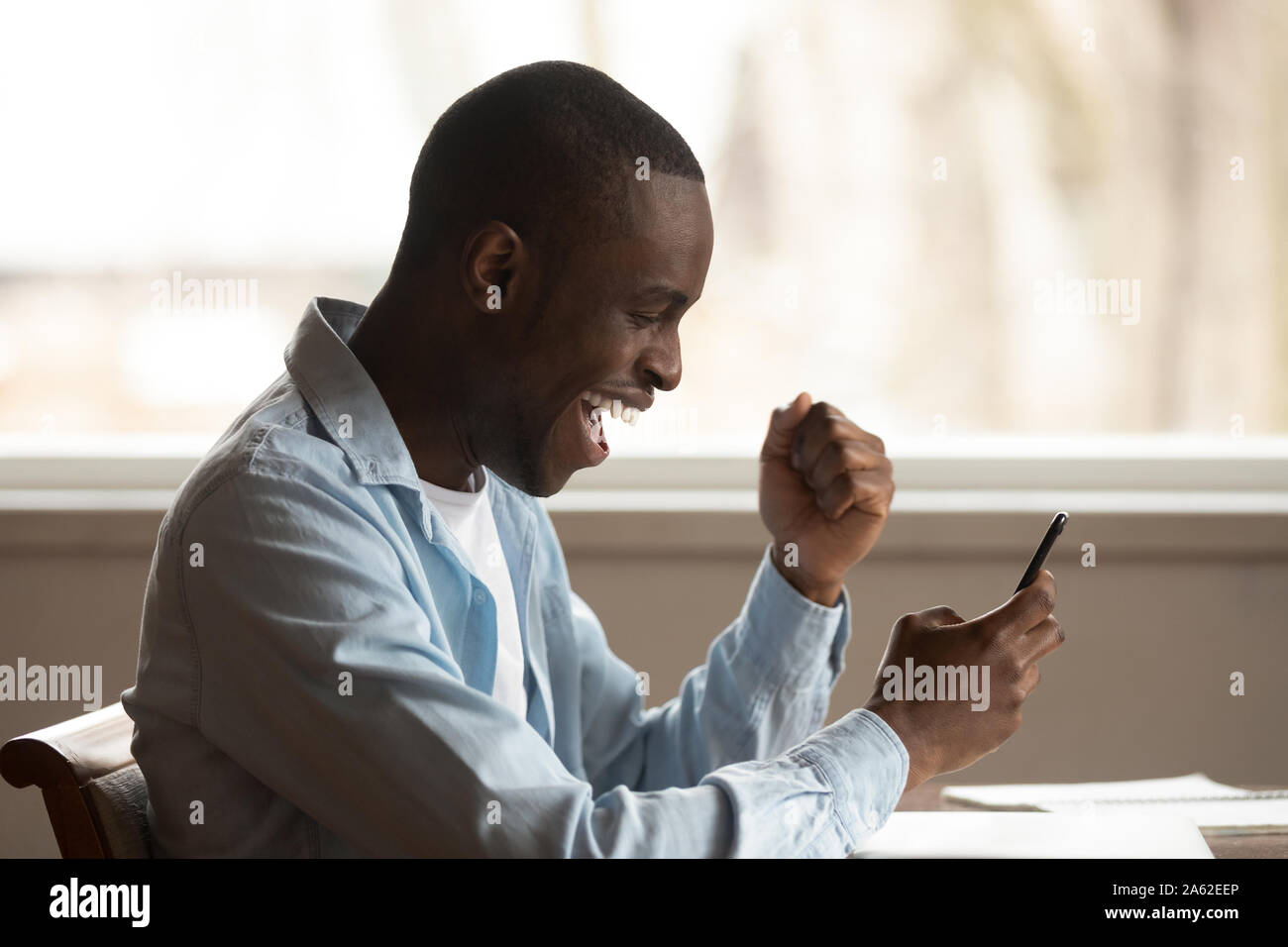 Excited lucky mixed race young man received win sms notification. Stock Photo