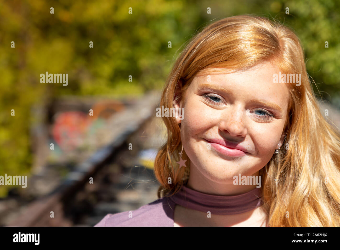 Portrait of gorgeous smiling teenage girl with red hair outdoors on sunny fall day Stock Photo