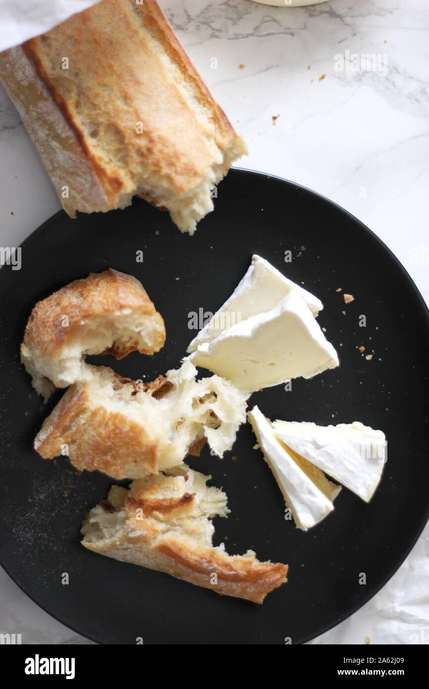 Overhead View of French Cheese Brie Slices with Crunchy Baguette. Traditional French products. Artisan Boulangerie Bread. Stock Photo