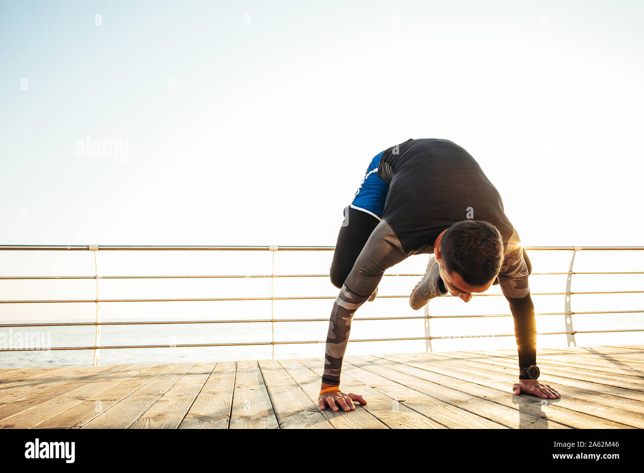 young man doing a bakasana, crane pose during an intense yoga practice Stock Photo