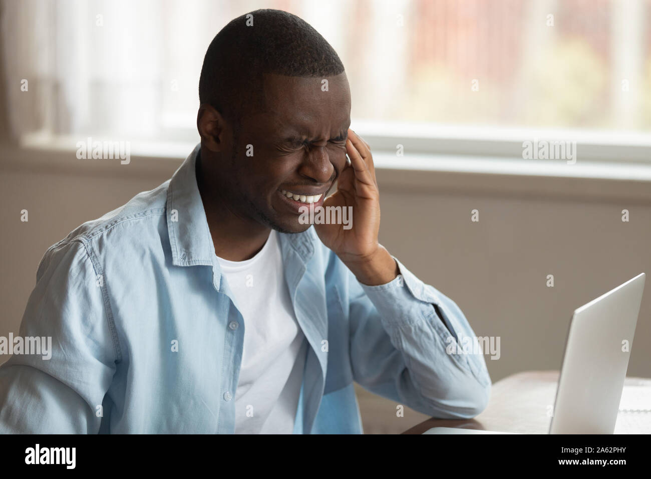 Unhappy tired african american guy suffering from sudden strong headache. Stock Photo