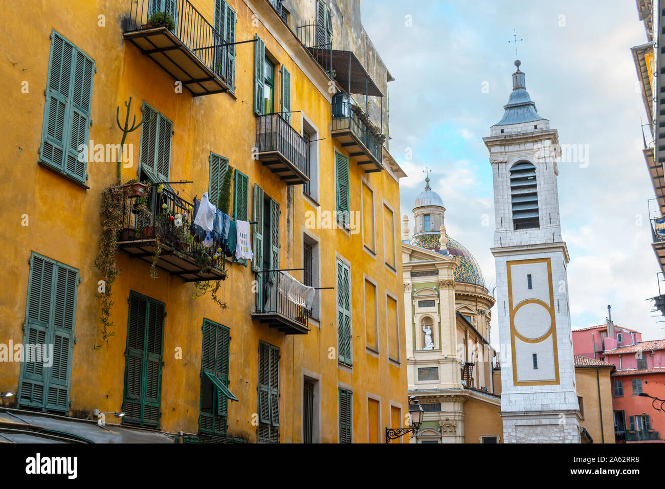 View of the campanile bell tower of the Nice Cathedral at Place Rossetti past an apartment building with laundry hanging in Old Town Nice France. Stock Photo