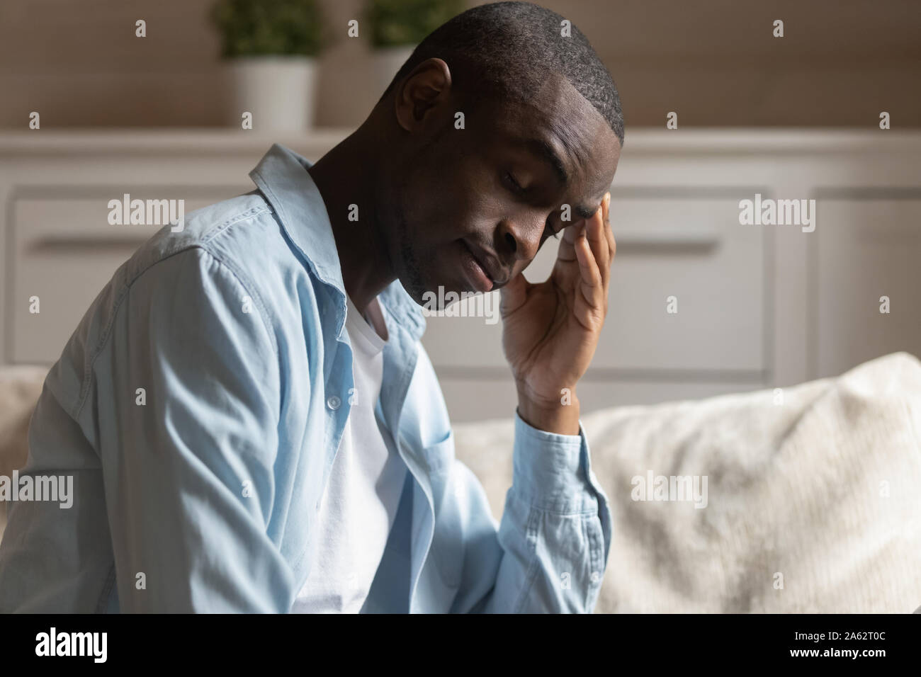 Exhausted young african american guy suffering from headache, feeling depressed. Stock Photo
