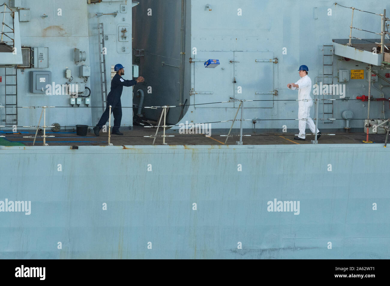 Royal Navy personnel loading provisions on HMS Westminster F237 frigate using a human chain or bucket brigade method of throwing boxes to each other Stock Photo