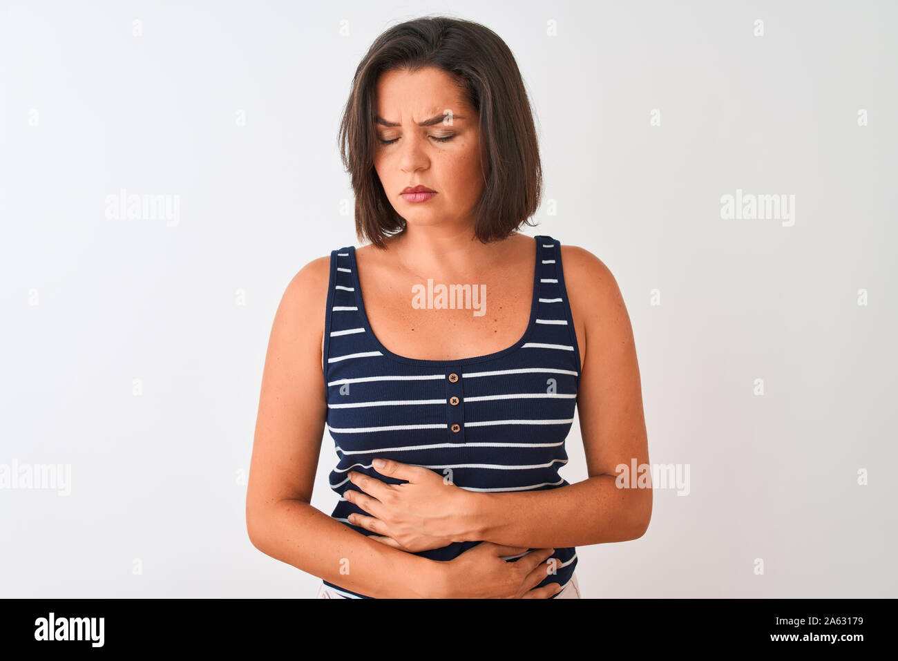 Young beautiful woman wearing blue striped t-shirt standing over isolated white background with hand on stomach because nausea, painful disease feelin Stock Photo