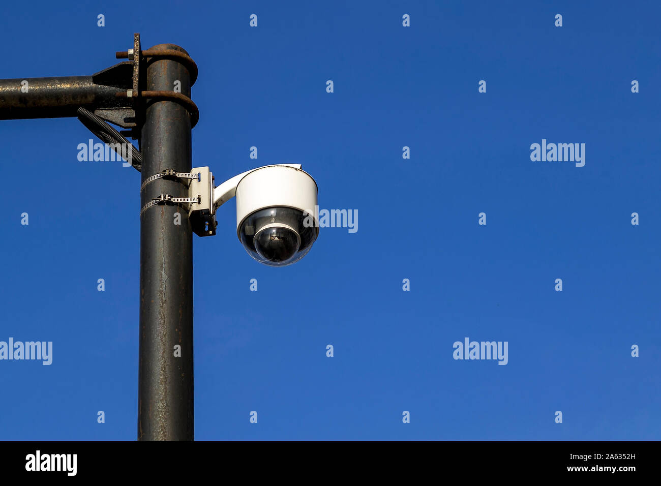 White street camera of external supervision installed on an outdoors pole against a blue sky. Modern CCTV camera, surveillance and monitoring. Copy sp Stock Photo