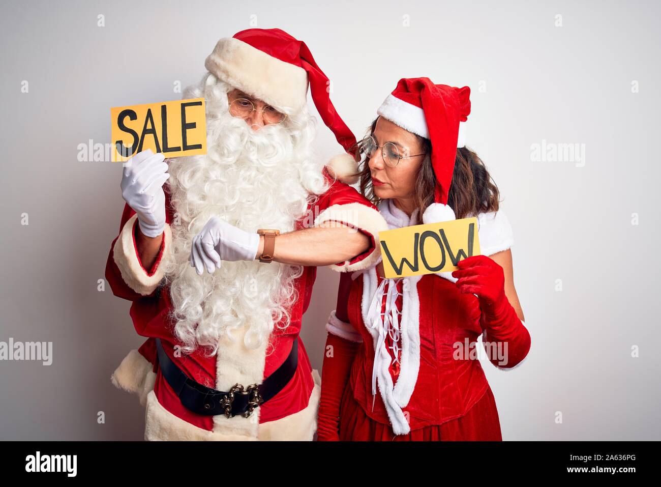 Couple wearing Santa costume holding wow and sale banner over isolated