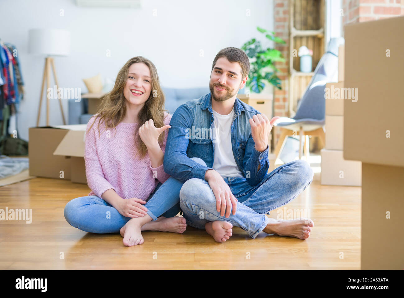 Young beautiful couple moving to a new house sitting on the floor ...