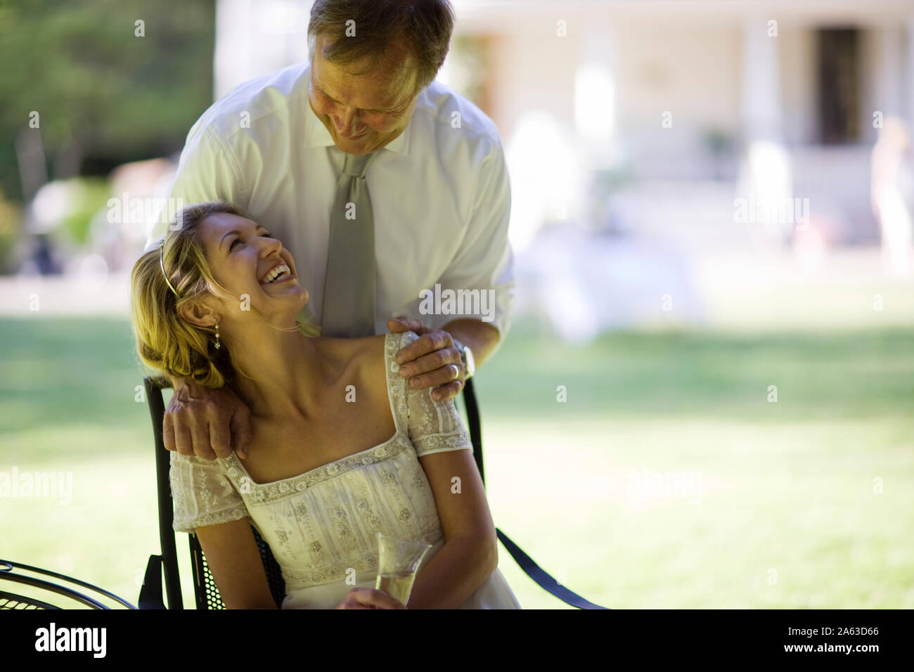 Mature adult man standing behind his young adult wife while she is 