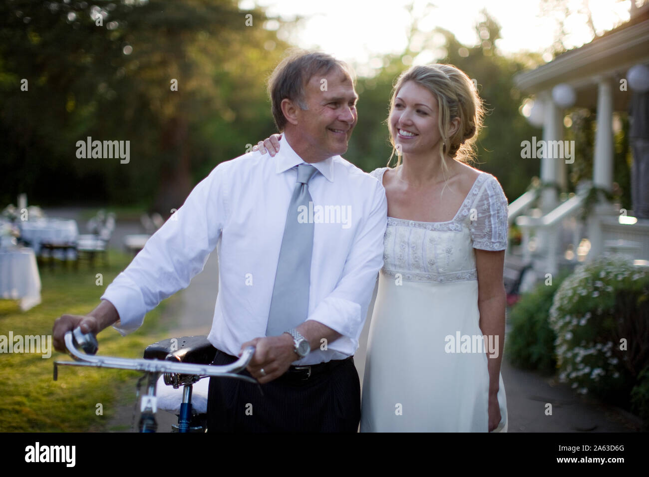 Mature adult man walking with his young adult wife while pushing a 