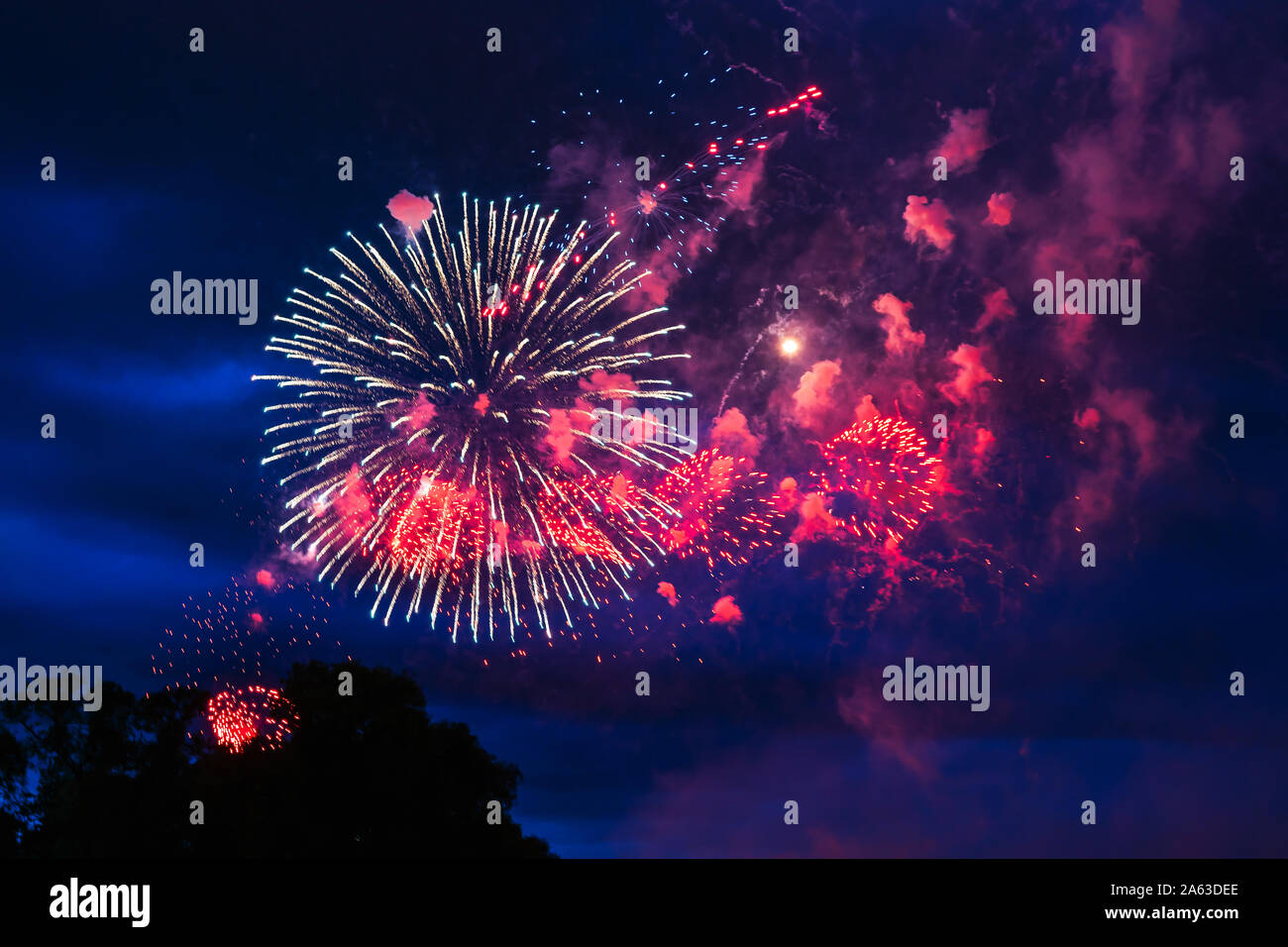 Inexpensive fireworks over the city red, pink and white. Bright and shiny. For any purpose. Celebration concept. Stock Photo